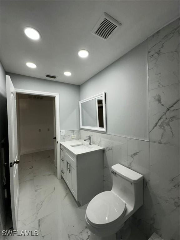 bathroom featuring vanity, toilet, and tile walls