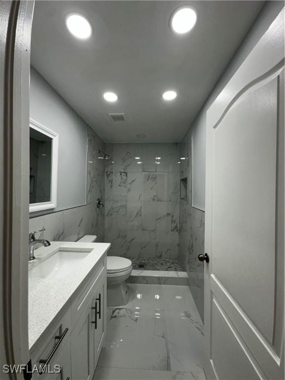 bathroom with vanity, toilet, and tiled shower