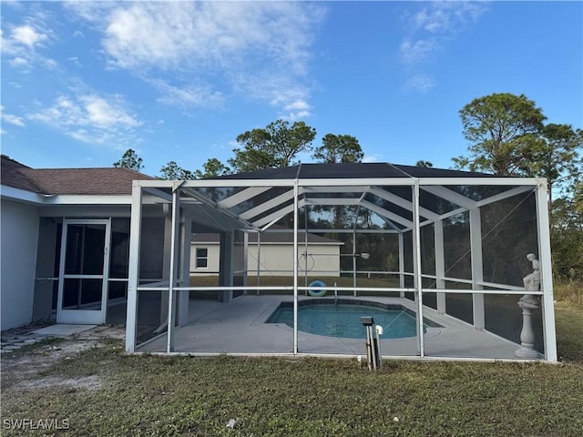 view of swimming pool with glass enclosure, a patio area, and a lawn