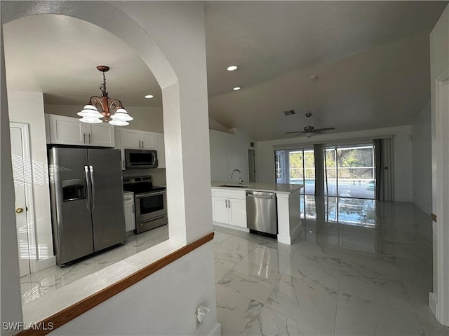 kitchen with pendant lighting, ceiling fan with notable chandelier, vaulted ceiling, white cabinetry, and stainless steel appliances