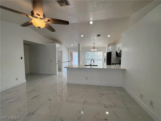 kitchen featuring kitchen peninsula, appliances with stainless steel finishes, sink, white cabinets, and lofted ceiling