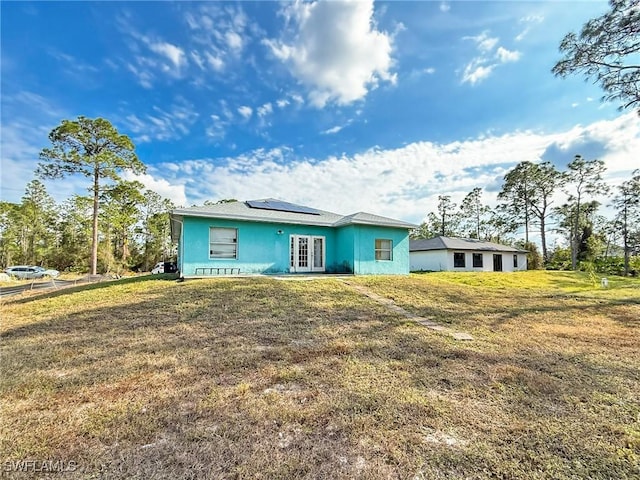 view of front of property featuring french doors, a front lawn, and solar panels