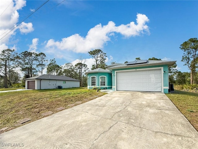 ranch-style home with a front yard, solar panels, and a garage