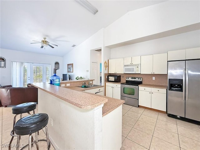 kitchen with a breakfast bar, appliances with stainless steel finishes, vaulted ceiling, and sink