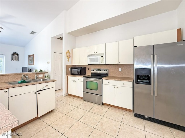 kitchen featuring decorative backsplash, white cabinets, stainless steel appliances, and vaulted ceiling