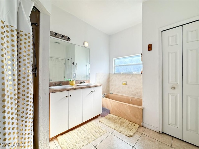 bathroom with tile patterned floors, a tub, and vanity