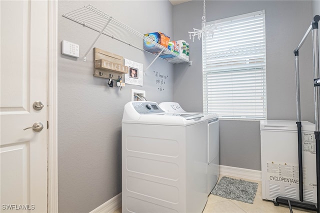 laundry room with a notable chandelier, washer and clothes dryer, and light tile patterned floors