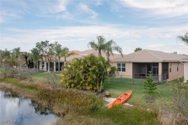 back of property featuring a lawn, a sunroom, and a water view