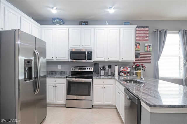 kitchen featuring stone countertops, white cabinetry, sink, light tile patterned floors, and stainless steel appliances