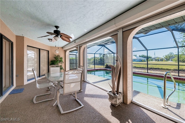 sunroom / solarium with ceiling fan and a swimming pool