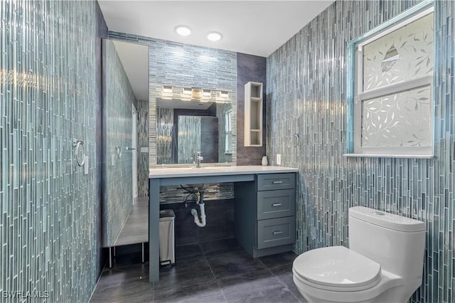 bathroom with sink, tile patterned flooring, tile walls, and toilet