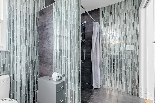 bathroom with a shower with curtain, toilet, tile walls, and tile patterned floors