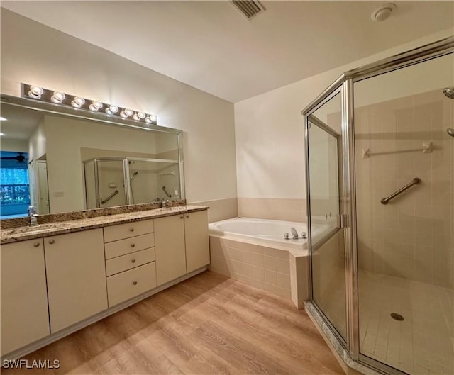 bathroom with hardwood / wood-style floors, vanity, and independent shower and bath