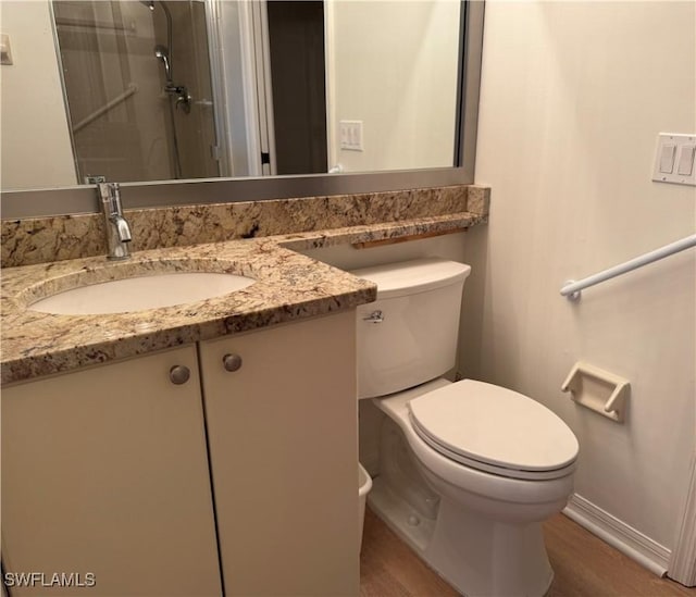 bathroom with walk in shower, toilet, vanity, and hardwood / wood-style flooring