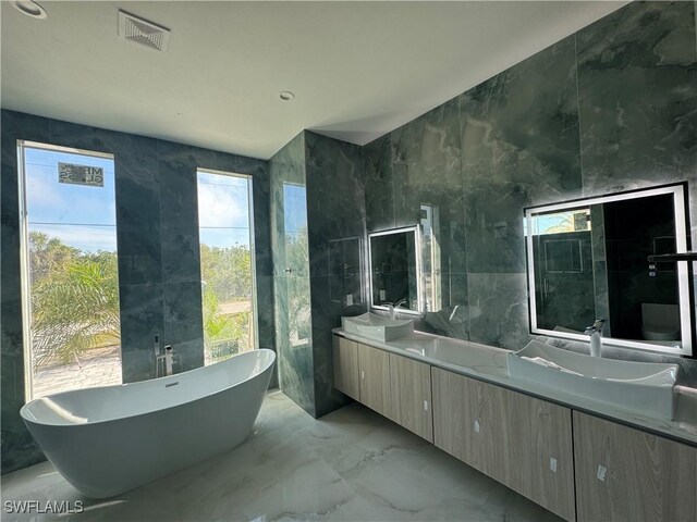 bathroom with tile walls, vanity, and a tub to relax in