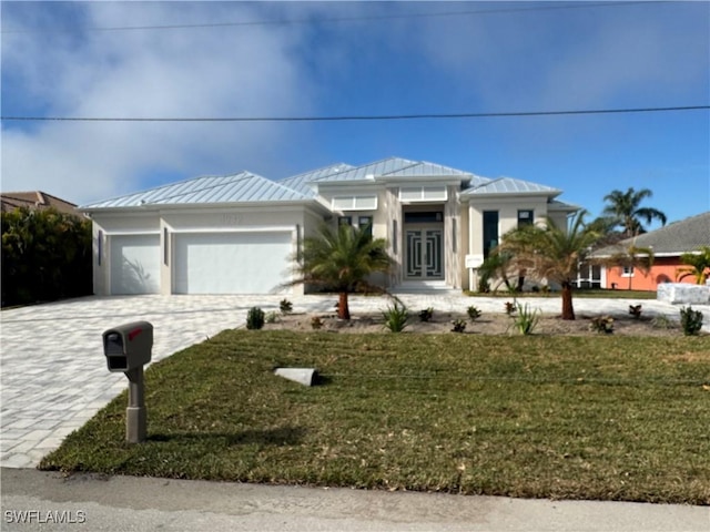 view of front of property with decorative driveway, a standing seam roof, metal roof, a garage, and a front lawn