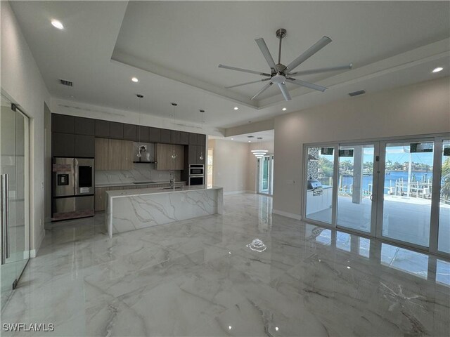 unfurnished living room with sink, a raised ceiling, and ceiling fan