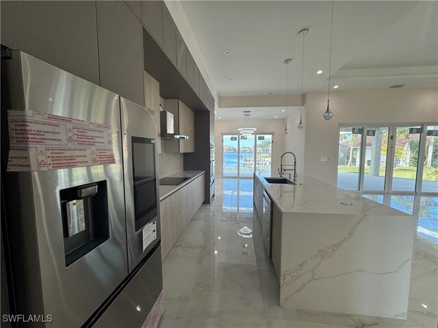 kitchen featuring gray cabinets, appliances with stainless steel finishes, decorative light fixtures, an island with sink, and sink