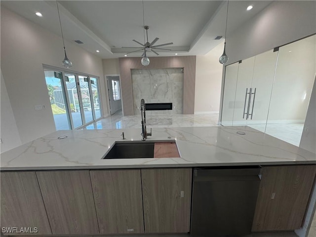 kitchen with pendant lighting, sink, light stone counters, and a high end fireplace