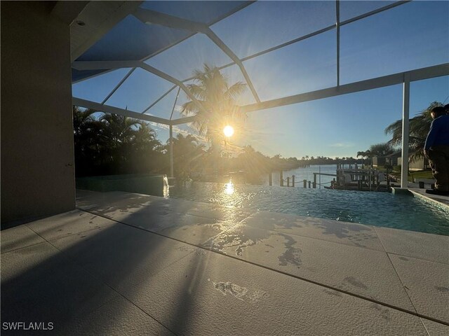 exterior space featuring a patio, pool water feature, glass enclosure, a water view, and a dock