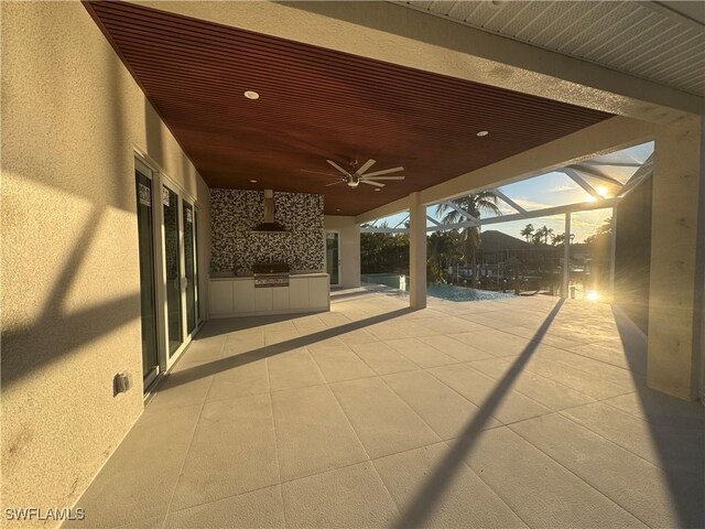 patio terrace at dusk featuring area for grilling, a lanai, and ceiling fan