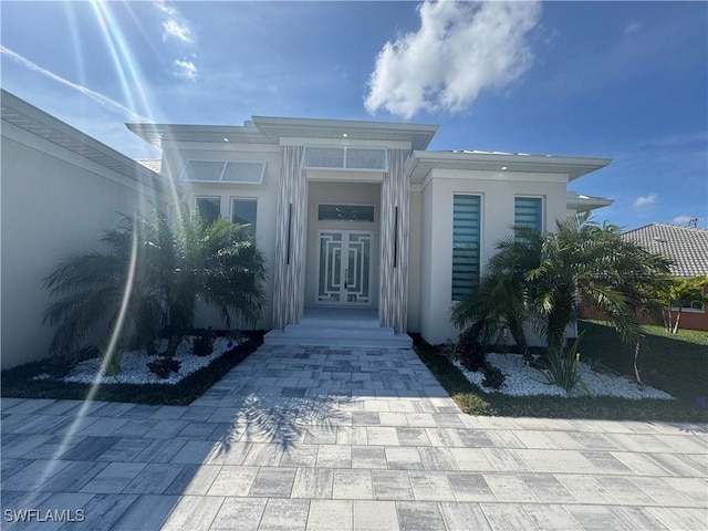 view of exterior entry featuring french doors and stucco siding