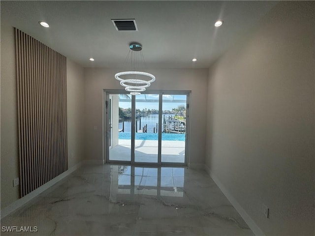 spare room featuring marble finish floor, a water view, and baseboards