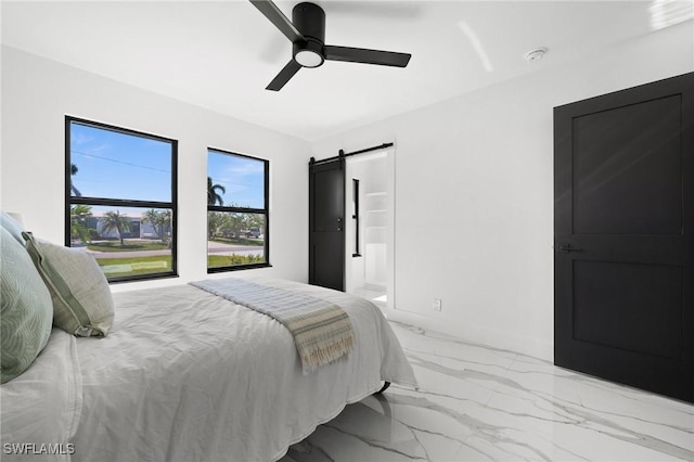 bedroom featuring a barn door, ceiling fan, and ensuite bath