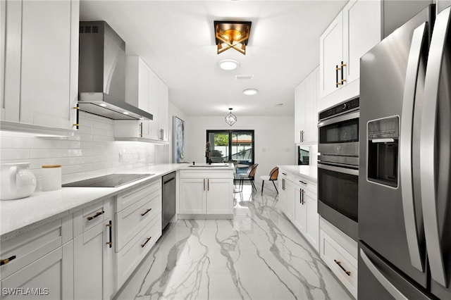 kitchen with white cabinets, backsplash, kitchen peninsula, stainless steel appliances, and wall chimney range hood