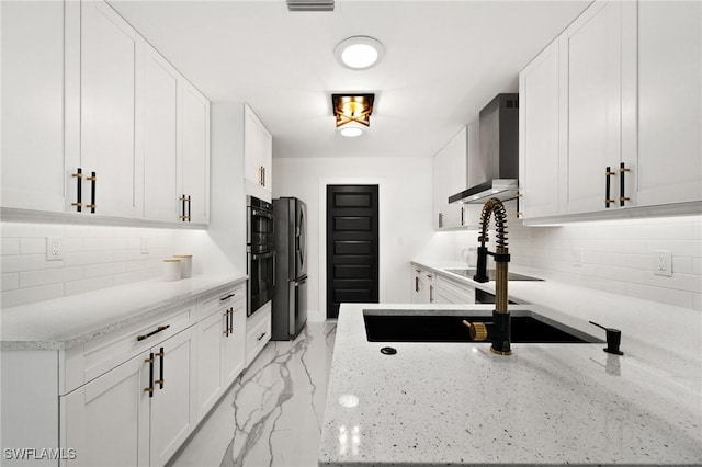 kitchen featuring wall chimney range hood, white cabinets, and decorative backsplash