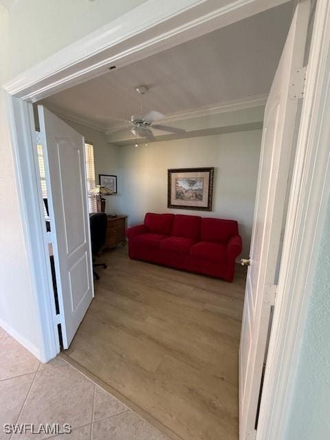 tiled living room with ceiling fan and ornamental molding