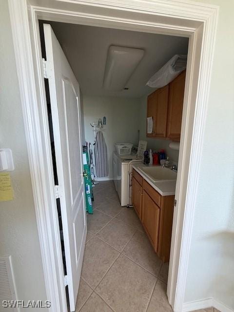 interior space with washer and clothes dryer, light tile patterned floors, cabinets, and sink