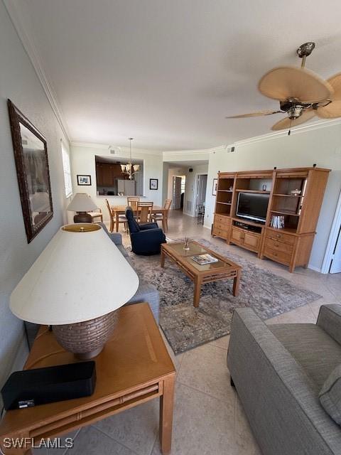 tiled living room with ceiling fan and crown molding