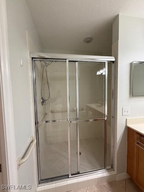 bathroom featuring a textured ceiling, vanity, tile patterned floors, and walk in shower