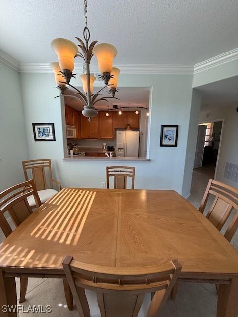 dining space featuring ornamental molding, a textured ceiling, and an inviting chandelier