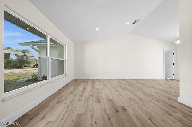 empty room featuring plenty of natural light, lofted ceiling, and light wood-type flooring