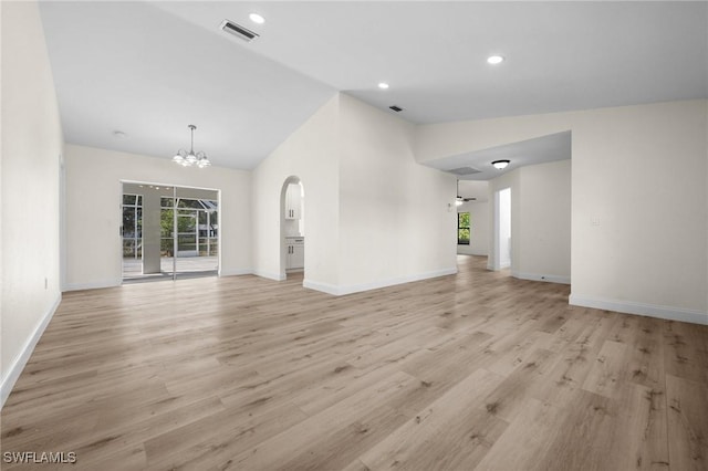 unfurnished living room with light hardwood / wood-style flooring, high vaulted ceiling, and ceiling fan with notable chandelier