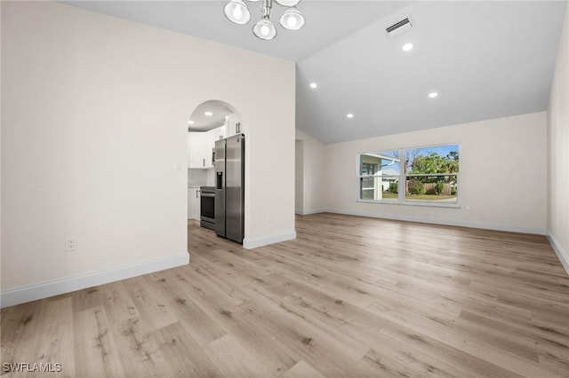 unfurnished living room with a chandelier, vaulted ceiling, and light wood-type flooring