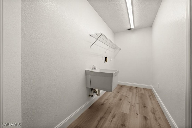 washroom featuring light hardwood / wood-style floors, sink, a textured ceiling, and hookup for a washing machine