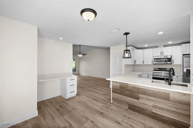 kitchen with white cabinetry, sink, hanging light fixtures, kitchen peninsula, and appliances with stainless steel finishes