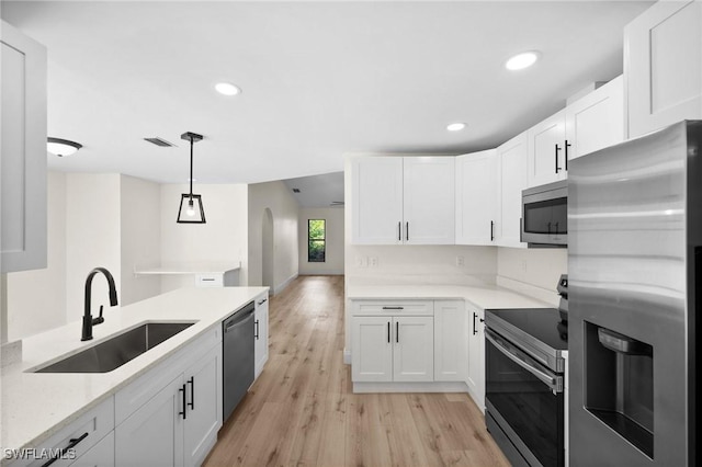 kitchen with appliances with stainless steel finishes, white cabinetry, and pendant lighting