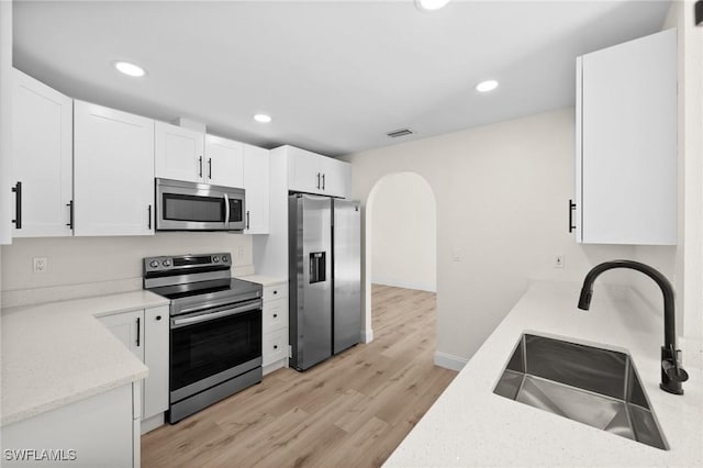 kitchen with white cabinets, light stone counters, sink, and stainless steel appliances