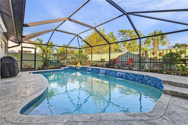 view of pool featuring pool water feature, a patio, a grill, and glass enclosure