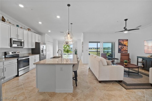 kitchen with white cabinets, a center island with sink, hanging light fixtures, and appliances with stainless steel finishes