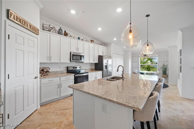 kitchen with a kitchen island with sink, sink, hanging light fixtures, white cabinetry, and stainless steel appliances