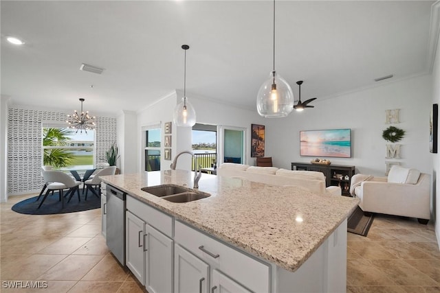 kitchen featuring sink, hanging light fixtures, light stone counters, an island with sink, and white cabinets