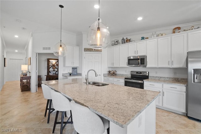 kitchen featuring appliances with stainless steel finishes, sink, decorative light fixtures, white cabinets, and an island with sink