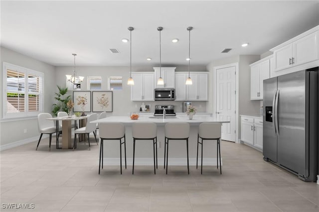 kitchen with white cabinetry, sink, hanging light fixtures, an island with sink, and appliances with stainless steel finishes