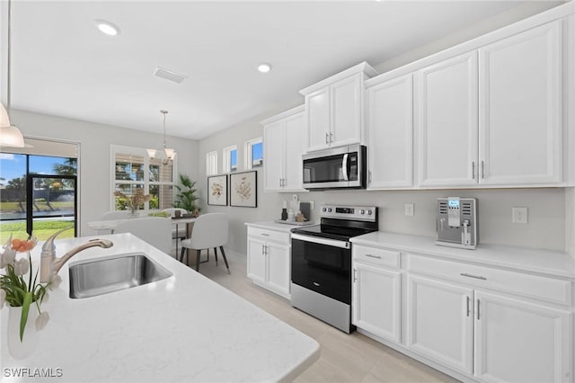 kitchen featuring pendant lighting, sink, white cabinets, and stainless steel appliances