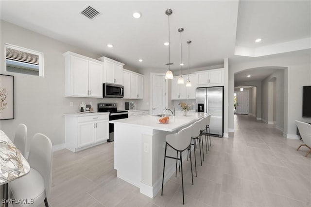 kitchen with pendant lighting, a center island with sink, white cabinetry, and stainless steel appliances